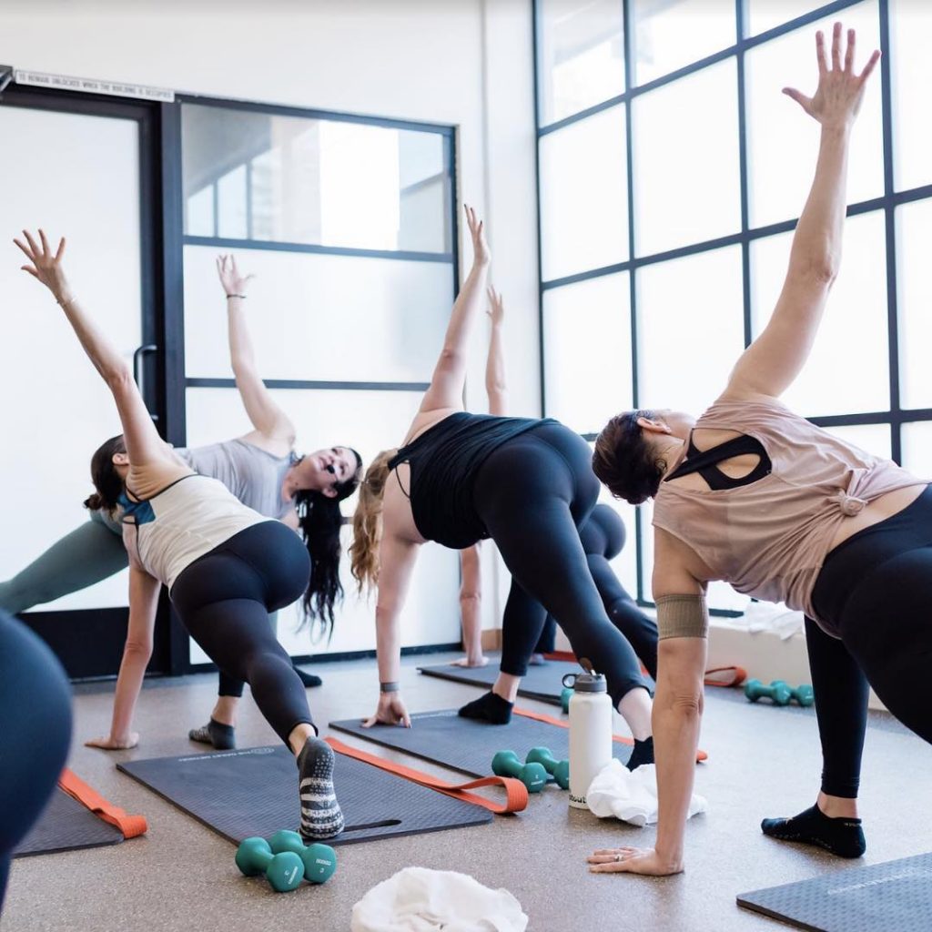 Women at a Dailey Method barre class in runner's lunge position.