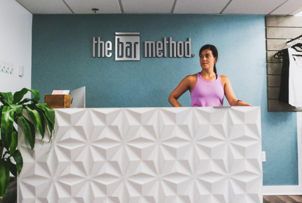 A Bar Method instructor stands behind the reception desk at the Rittenhouse location.