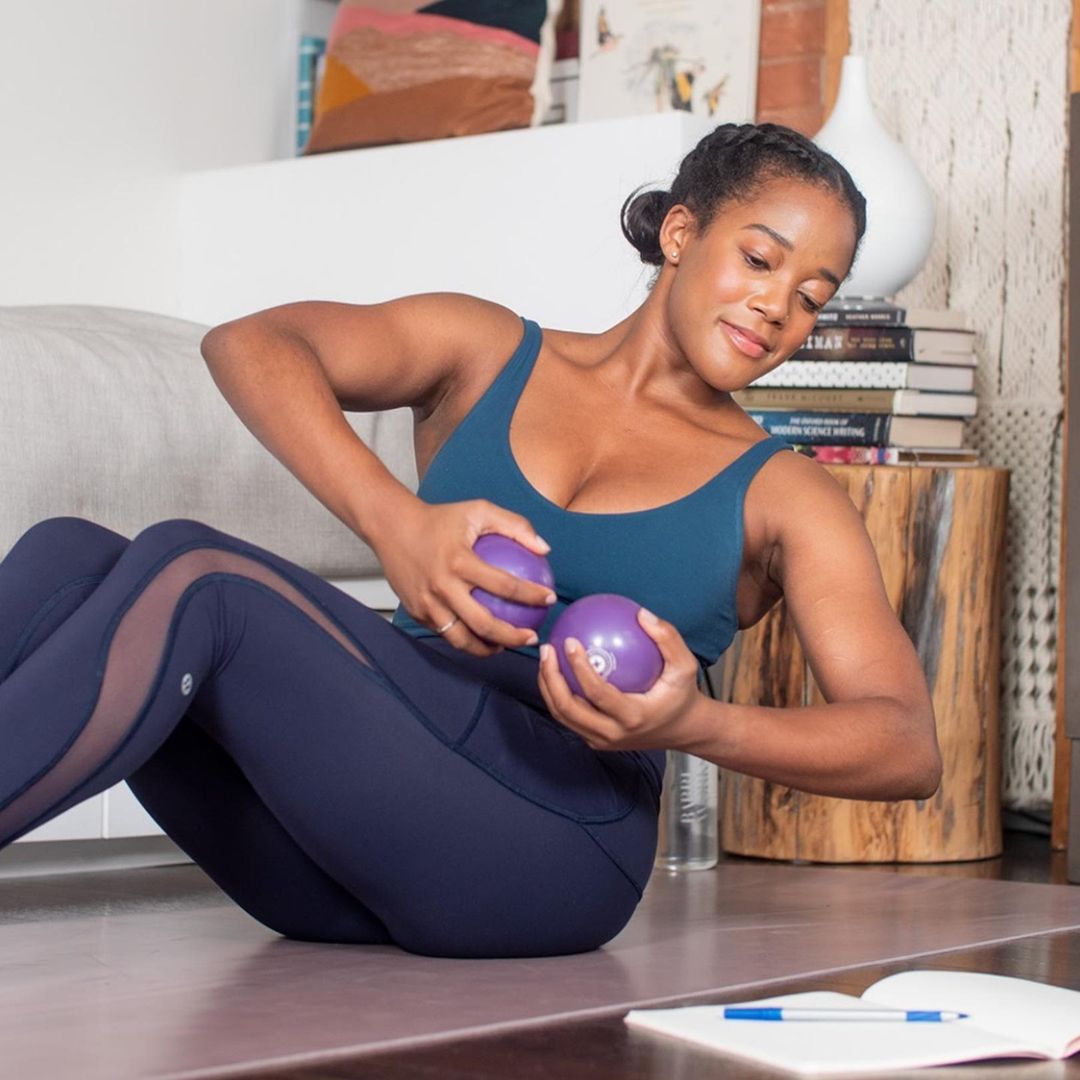 A woman works out at home while studying for a Barreworks barre certification.